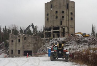 Two Démex excavators working on a building where the front portion is halfway through demolition