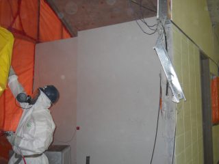 An employee wearing proper PPE's removing asbestos inside an auditorium