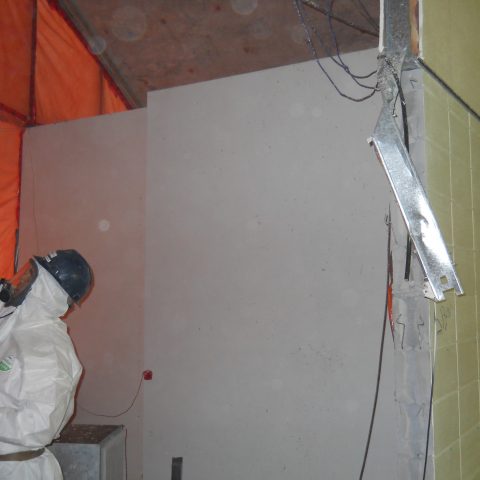 An employee wearing proper PPE's removing asbestos inside an auditorium