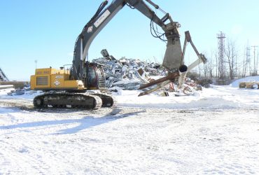 Une excavatrice Démex équipée d'une puissante cisaille qui manipule et découpe des débris métalliques.