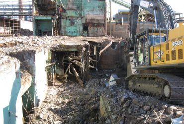 Démex excavator demolishing ground level building structures