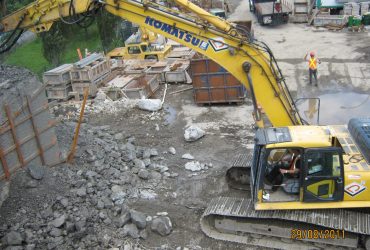 One Démex excavator and an employee on the bridge during day time