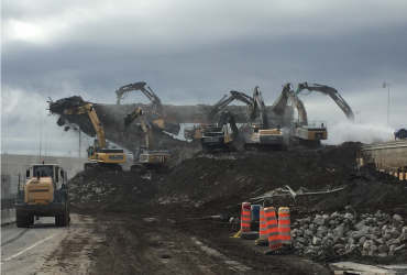 A wheel loader and seven excavator at work demolishing a massive scection of the bridge