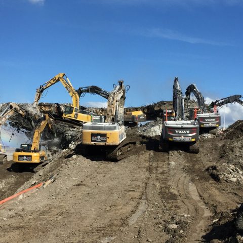 Eight excavators crushing concrete from the bottom and from the top of what is remaining from the bridge center support structure