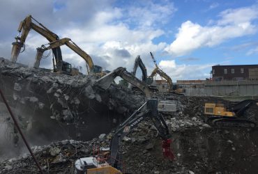 Seven excavators equiped with a shear doing demolition work