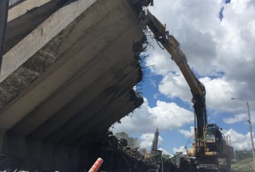 Vue impressionnante du bas vers le haut d'une excavatrice s'attaquant à la structure de support massive en béton.