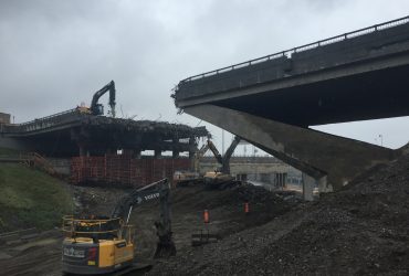 Four Démex excavators equiped with hydraulic hammers and buckets busy demolishing bridge elements