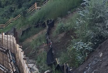 Vue d'une membrane noire à la verticale, environ deux pieds de haut à partir du sol en pente à titre de mesure environnementale pour gérer l'écoulement d'eau de surface.