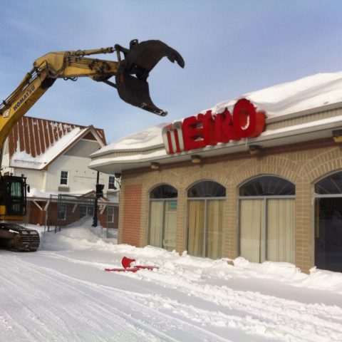 A Démex excavator about to tear down the front wall of a Metro store.