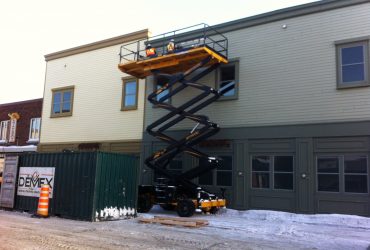 Plate-forme élévatrice à ciseaux permettant à deux employés de Démex de s’acquitter de leurs tâches.