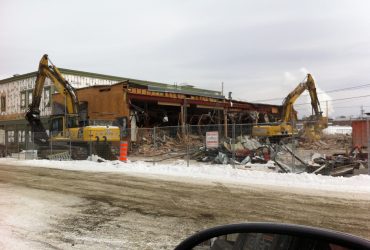 Deux excavatrices Démex démolissant un bâtiment commercial en hiver.