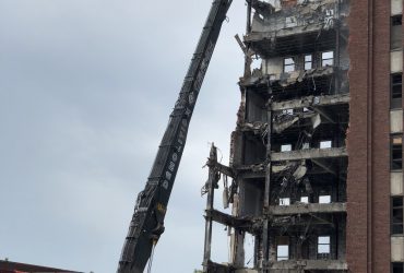 Vue d'une excavatrice à longue portée qui s'attaque aux parties surélevées d'une des ailes de l'hôpital.