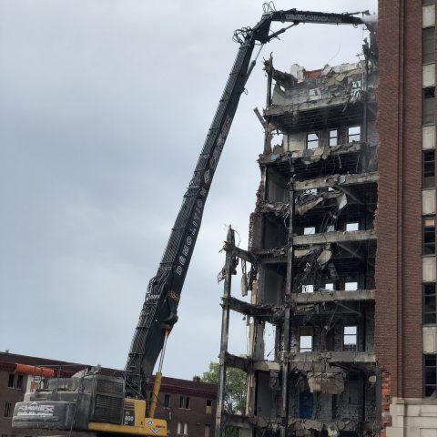 Vue d'une excavatrice à longue portée qui s'attaque aux parties surélevées d'une des ailes de l'hôpital.