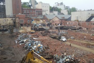 Distant view of the site showing several buildings already removed and a truck on the site