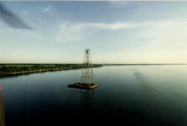 Pylône partiellement démantelé en sa partie supérieure, au milieu du fleuve, par beau temps.