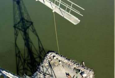 Structure métallique de pylône retenue par câbles et abaissée vers la barge sur le fleuve