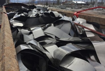 Vue d'une grande benne emplie de feuilles métalliques coupées pour fin de recyclage.