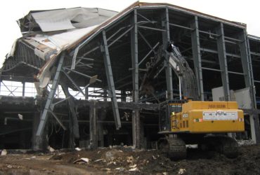 An excavator tearing down a building with a metal structure