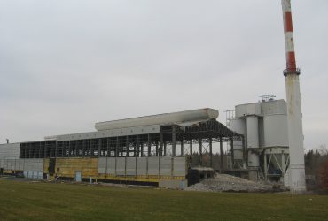 Picture showing a stack and a long building with siding removed