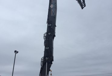 View of the PC 800 excavator with the long reach boom extended vertically and the last section pointing down