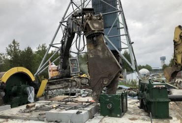 Vue d'une excavatrice Démex munie d'une puissante cisaille en train de couper un élément métallique.