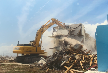Excavator equiped with a concrete crusher tool demolishing a concrete structure