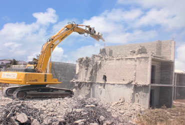 Excavator equiped with a concrete crusher tool demolishing a concrete structure