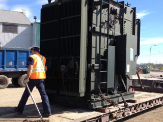 Vue d'un employé Centrem en train de vérifier l'installation d'un transformateur sur fardier