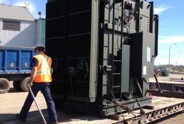 Vue d'un employé Centrem en train de vérifier l'installation d'un transformateur sur fardier