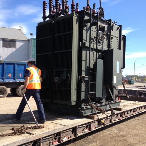 A Centrem employee verifying proper stowage of a tranformer onto a low deck trailer