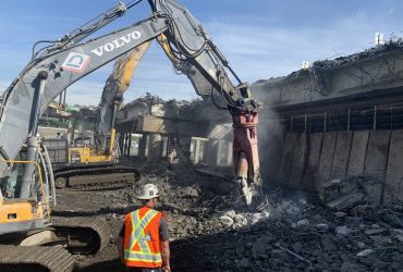 Vue d'un employé Démex surveillant des excavatrices broyant du béton.