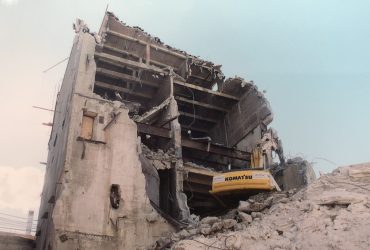 Vue d'une excavatrice en train de démolir un bâtiment en béton à l'ancienne usine de pâte à Kénogami.