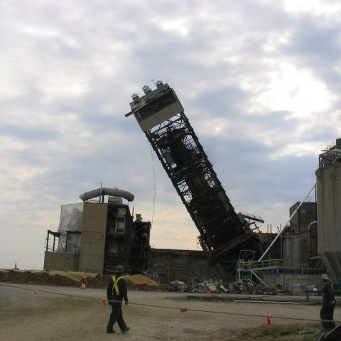 Vue de la structure métallique de l'ancien atelier de production d'acide de Tembec tombant au sol, à Kapuskasing en Ontario.