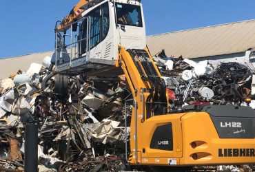 Vue d'une excavatrice de manutention Centrem eb train de manipuler des métaux empilés au centre de recyclage Centrem à Alma.