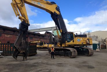 Démex PC 800 excavator equiped with a powerful shear, idle with demolition tool on the groud and a Démex employee near the tracks