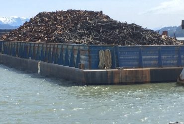 Barge loaded with scrap ferrous metals with scenic view in the back