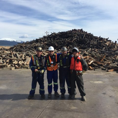 Four Centrem employees next to a pile of scrap ferrous metal on a barge