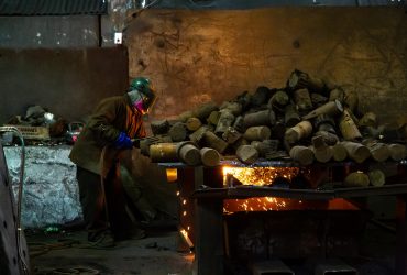 Vue à l'intérieur du centre de recyclage d'un employé Centrem avec EPI coupant un rondin à la torche.