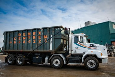 Roll-off truck moving with container at Centrem recycling center in Alma
